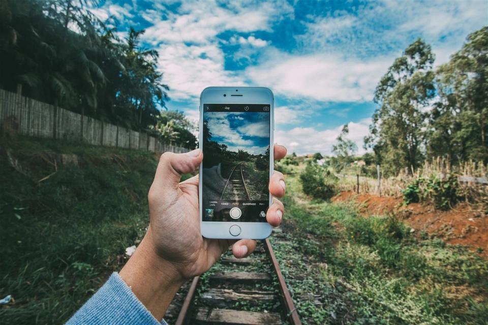 Une personne prend une photo depuis son smartphone d'une ancienne ligne de chemin de fer