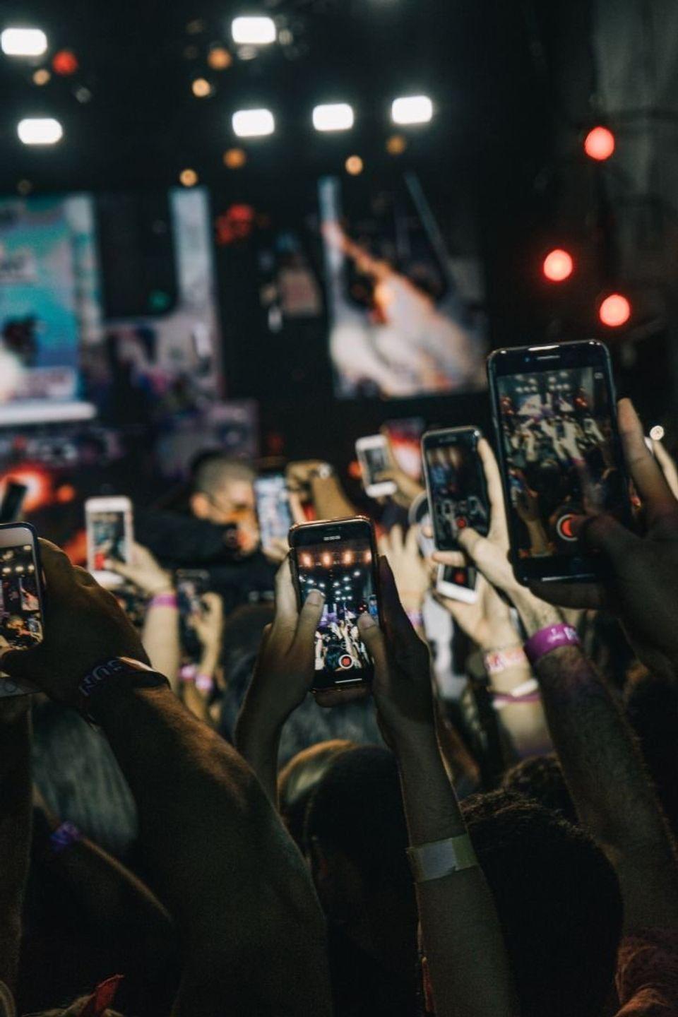 Plusieurs personnes prennent en photo/video un concert depuis leurs smartphone